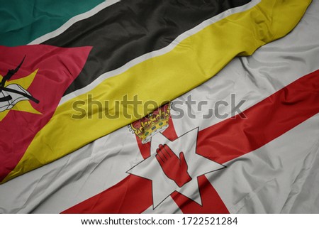 waving colorful flag of northern ireland and national flag of mozambique. macro