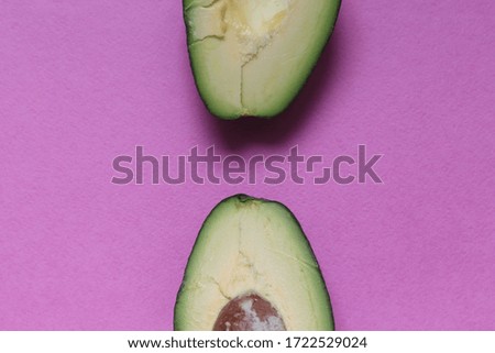 cut ripe green avocado on a pink background, top view