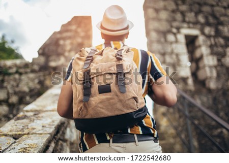 Handsome tourist with backpack is making travel across city.
