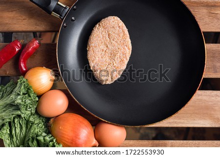 Raw cutlet in a frying pan. Cooking in the country. The view from the top.