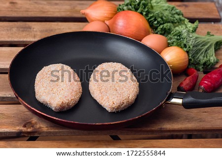 Two raw cutlets in a frying pan. The view at 45 degrees.