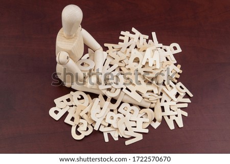 Wooden man sitting in heap of letters. Information or education concept.