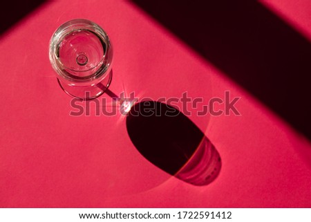 Exquisite glass of water on a pink background, top view. Vocal composition in harsh light. Space for inscription.