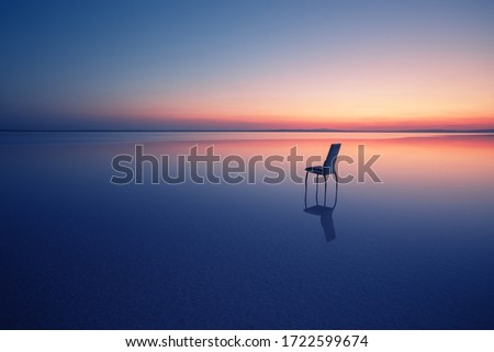 Chair among smooth water of lake at sunset. The concept of solitude and unity with nature. A chair stands in the water of the Salt Lake Ace. Anatolia, Turkey Royalty-Free Stock Photo #1722599674