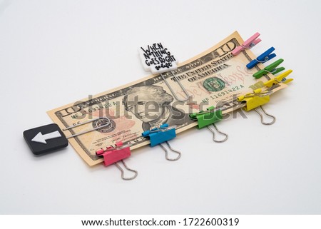 Ten dollar bill and multicolored paper clips and clothespins with the motto, when nothing goes right go left, obligations