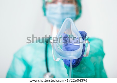 Doctor Woman holds Oxygen Mask for Inhale breath problem Patient, Coronavirus or Covid-19 attack Lungs. Healthcare worker in protective equipment put on oxygen mask patient diagnosis of coronavirus Royalty-Free Stock Photo #1722604396