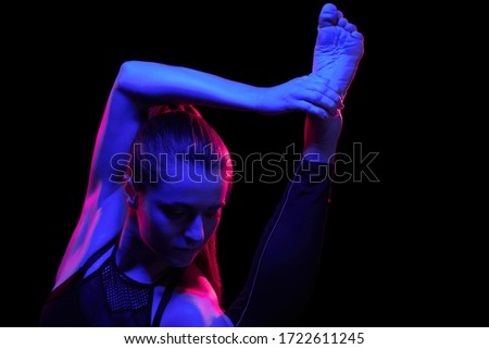 Young fit woman practicing yoga. Neon light. Modern sci fi representation of yoga. Copy space