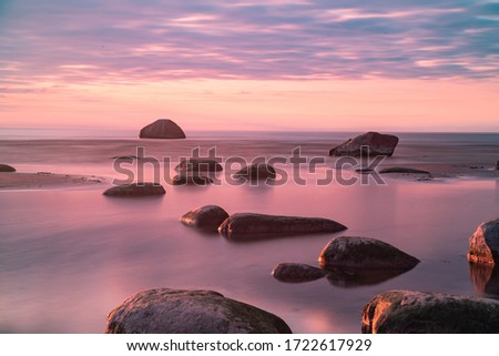 Amazing perfect pink dreamy looking sunset. Slow shutter speed photos of sunset. Smooth water and colorful clody sky. Sunset through straws. Stones on the beach. Wallpaper. Little blur - dreamy look