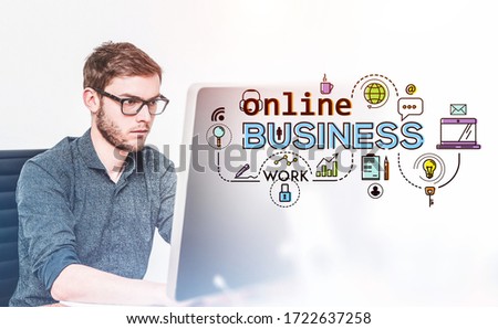 Serious young man in glasses and casual clothes using computer in blurry room with double exposure of online business icons. Concept of work during covid 19 coronavirus pandemic. Toned image
