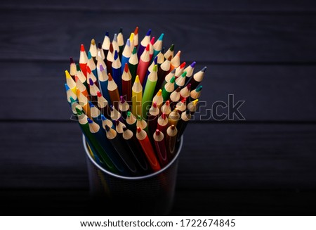 Colorful pencils in metal holder on the wood vintage background