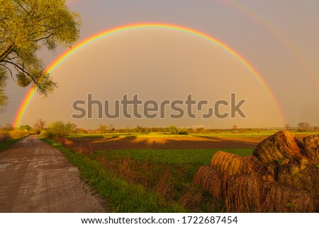Rural landscape with rainbow after rain. Sky after storm and rain. Idyllic.