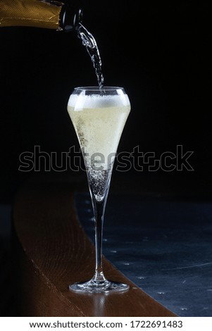 Sparkling wine is poured into a glass on a bar counter. Champagne