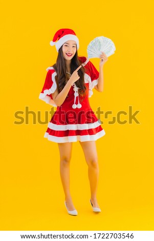 Portrait beautiful young asian woman wear christmas clothes and hat with cash and money on yellow isolated background