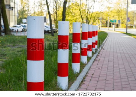 Red-white columns standing near the sidewalk.