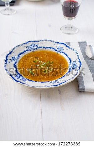 Classic french onion soup on a white wood table with some red wine and a silver spoon on the side