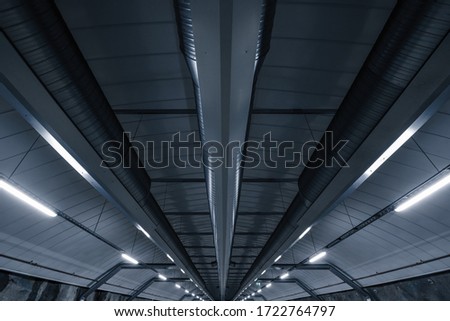 Sci fi looking dark and moody underground parking lot with fluorescent lights on.  Ceiling shot