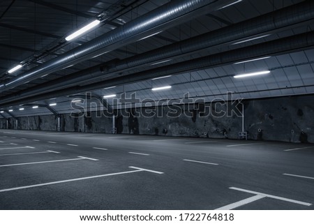 Sci fi looking dark and moody underground parking lot with fluorescent lights on.  Long hall