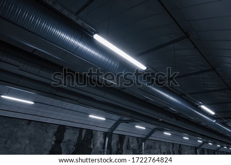 Sci fi looking dark and moody underground parking lot with fluorescent lights on.  Ceiling shot