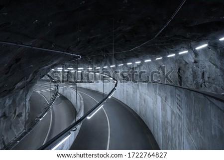 Sci fi looking dark and moody underground parking lot with fluorescent lights on.  Crossing roads, exit way