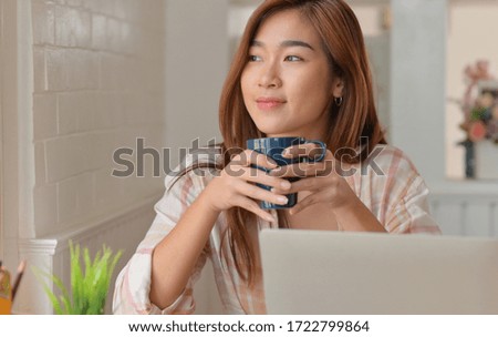 Teenage student smile and drink coffee while studying online from their home laptop.