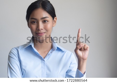 asian woman pointing one finger; portrait of positive happy smiling asian woman pointing up one finger for first winner concept ; southeast asian adult woman model