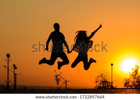 Couple jumping in sunset.Young man and woman having fun at sunset. Guys hanging together.