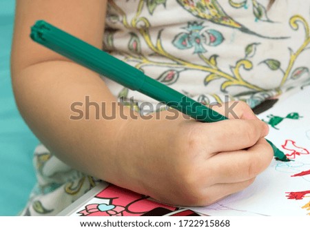 A girl hold green magic pen on right hand for writing.