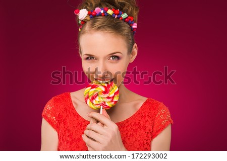 Lollipop. Girl with sweet candy in their hands. Red background. Studio photography.
