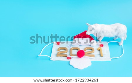 New year numbers 2021, Santa Claus hat and white ox on face mask on a blue background, creative minimal concept of Christmas 