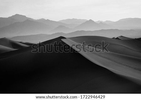 Black & White Image of Mesquite Flat Sand Dunes and Desert with Mountains in the Distance, located in Death Valley National Park in California Royalty-Free Stock Photo #1722946429