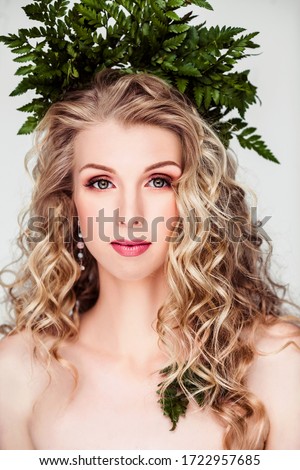 Portrait of a blonde girl with curly hair in a crown of fern.Photo on a white background in the studio.