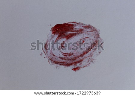 Red Lipstick smudge with glitter on a white background.
