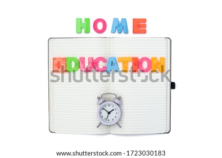 Colored plastic letters of the English alphabet, alarm clock and a notebook on a white background. Children education