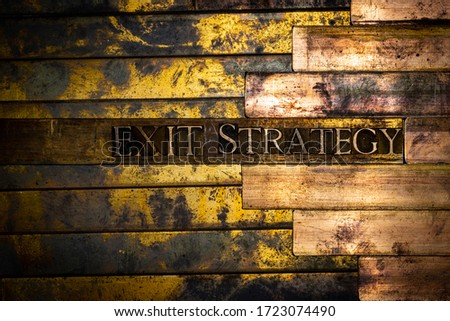Photo of real authentic typeset letters forming Exit Strategy text on vintage textured grunge copper background