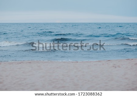 Sea coast with blue water. Stormy weather on the lake. Sandy beach with waves in bad weather. Nothern sea in wind.