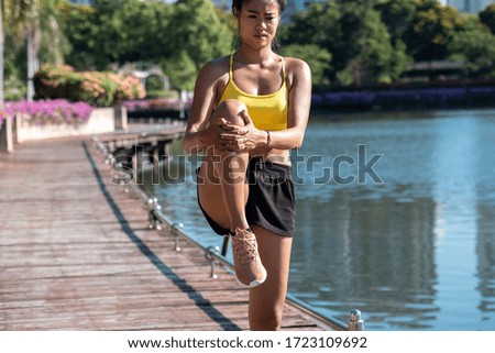 Fit woman stretching before working out stock photo. Fit sportswoman doing leg stretches in city park outdoors