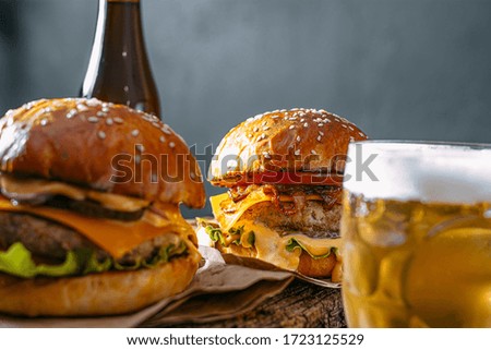 two delicious beef burger on a wooden table near two glass of cold beer