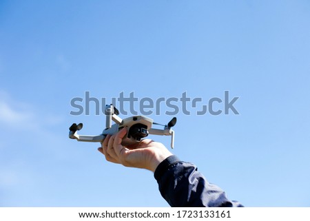 A man catching a drone with his hand with blue sky on a background