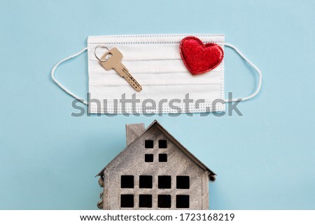 Sweet home concept, surgical mask, mini house and red heart on blue background, top view, flat layout