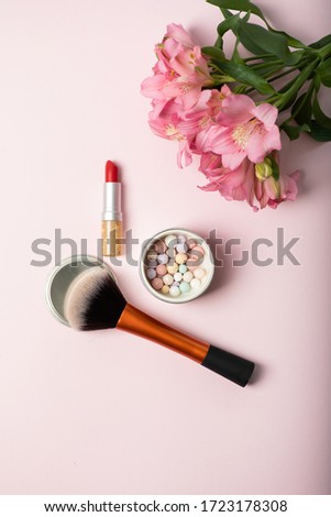 Make-up powder brush, powder in balls, red lipstick and beautiful pink bouquet of flowers. Womens make-up kit, gift for girl concept Royalty-Free Stock Photo #1723178308