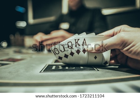 defocused blured view on player shows flash royal in poker against the background of playing chips on a green table in a casino close-up
