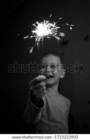 
happy baby with sparklers in hands. Image with nose effects. Image with selective focus.