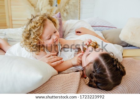 Happy loving family. Mother and daughter play and hug. The morning together. Happy games in the bedroom.