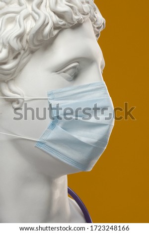 Medical protective mask on the face of the statue of Apollo.