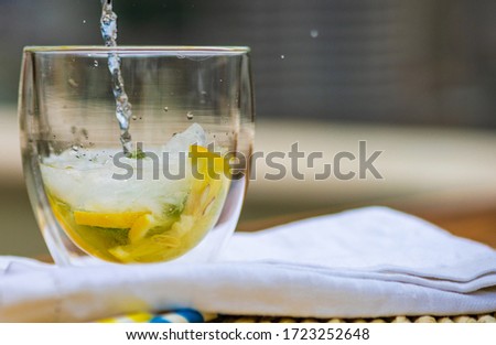 Tasty gin and tonic cocktail with slices of lemon and fresh mint on rustic background with copy space