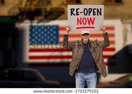USA protester with cap and sunglasses demonstrate against stay-at-home orders due to the COVID-19 pandemic with sign saying Re-open Now. American flag in background. Concept image with copy space.