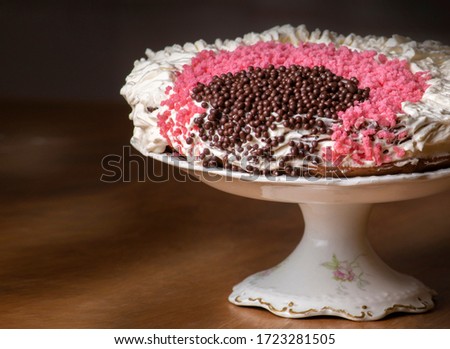 close-up of cake decorated with cream, chocolate sprinkles and pink sugar