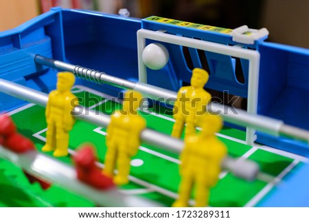 Football table, yellow and red dolls, side view with the ball entering the goal, fun for leisure hours.