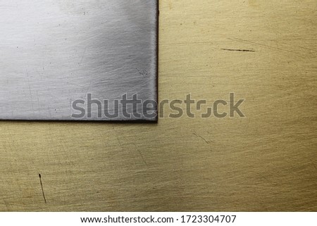 Old scratched metal. Corner of a steel plate on a copper background