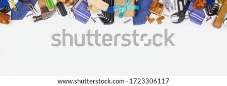Fathers Day theme long border of gifts, ties, games and tools on a white  banner background. Above view with copy space.